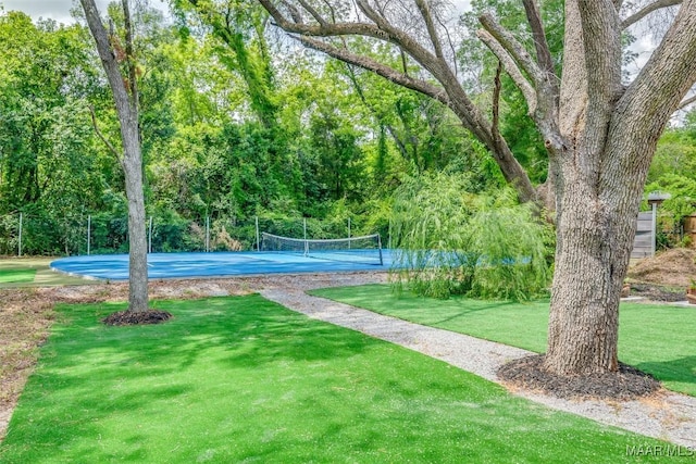 view of home's community with a tennis court, fence, and a yard