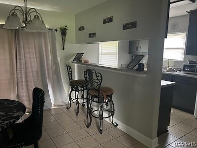 kitchen with a chandelier, light tile patterned flooring, a kitchen breakfast bar, light countertops, and hanging light fixtures