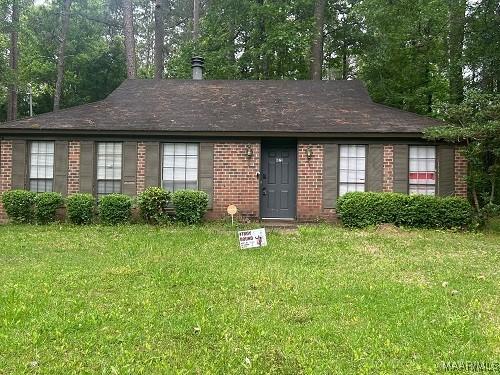 ranch-style house with a front yard and brick siding