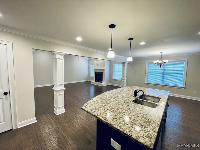 kitchen with crown molding, a sink, a fireplace with raised hearth, baseboards, and dark wood-type flooring