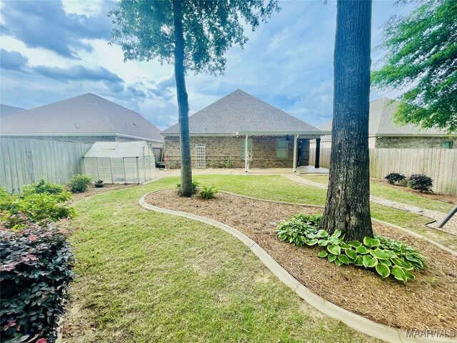view of yard featuring fence, an exterior structure, and an outbuilding