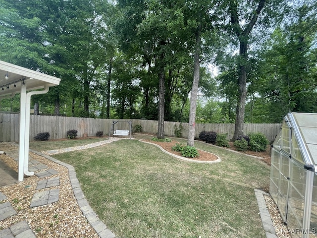view of yard with an outbuilding, a fenced backyard, and a greenhouse