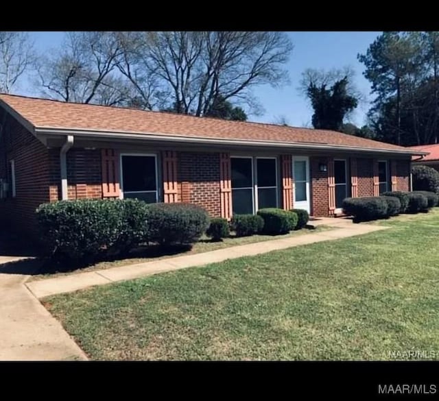 ranch-style house featuring brick siding and a front yard