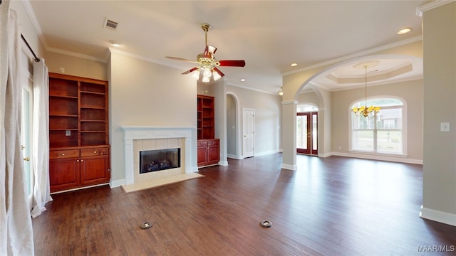 unfurnished living room featuring dark wood-style flooring, arched walkways, a tiled fireplace, ceiling fan with notable chandelier, and visible vents
