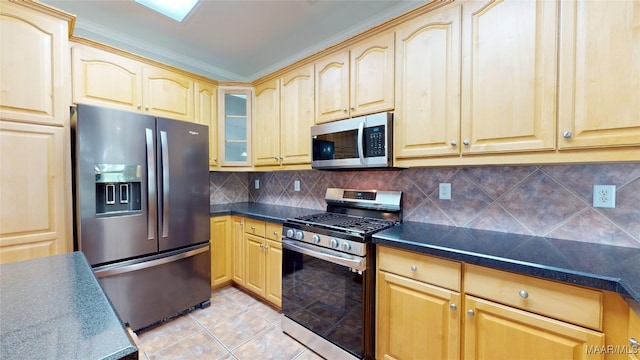 kitchen with decorative backsplash, appliances with stainless steel finishes, light tile patterned flooring, and dark countertops