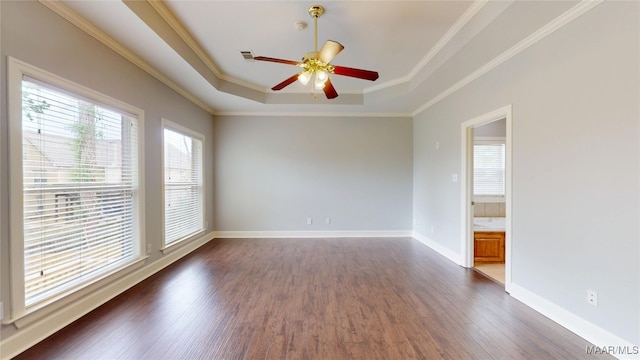 empty room featuring visible vents, baseboards, dark wood-type flooring, a raised ceiling, and a ceiling fan