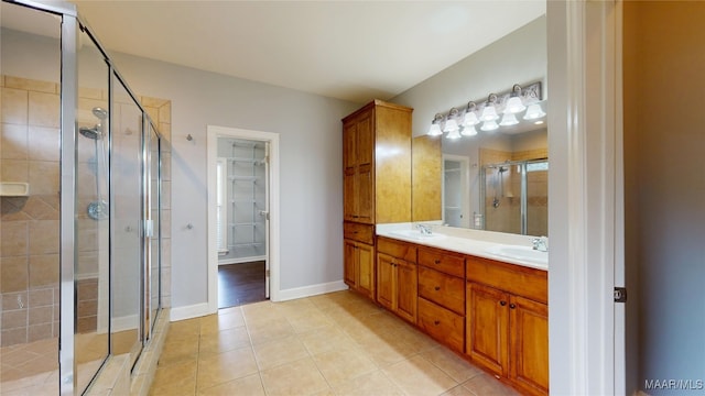 full bathroom featuring a sink, tile patterned floors, a stall shower, and double vanity