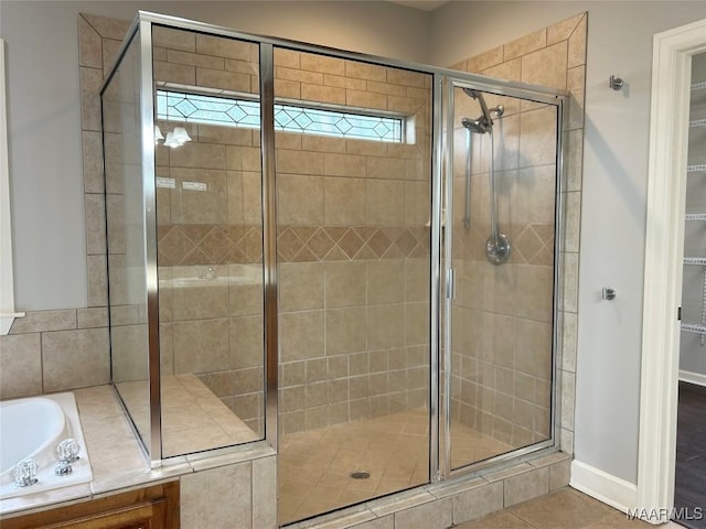 full bathroom featuring tile patterned flooring, a bath, and a shower stall