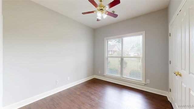 empty room with baseboards, dark wood-type flooring, and ceiling fan