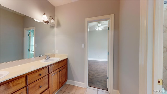 bathroom with tile patterned flooring, a ceiling fan, double vanity, baseboards, and a sink