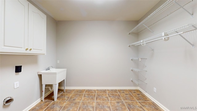 laundry area featuring baseboards and cabinet space