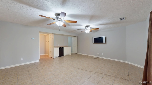 unfurnished room featuring visible vents, a textured ceiling, baseboards, and ceiling fan