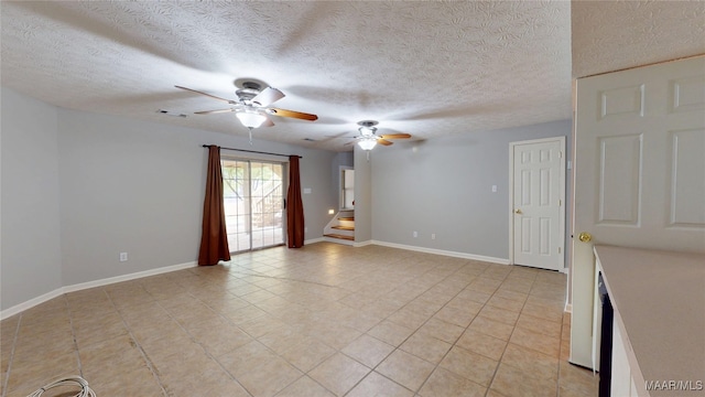 spare room with ceiling fan, a textured ceiling, visible vents, stairs, and light tile patterned flooring