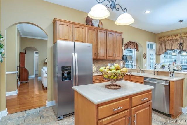 kitchen with decorative backsplash, a center island, light countertops, arched walkways, and stainless steel appliances