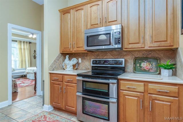 kitchen featuring light countertops, stainless steel appliances, light tile patterned flooring, and tasteful backsplash