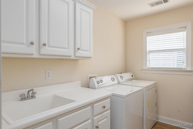 clothes washing area featuring visible vents, baseboards, washing machine and clothes dryer, a sink, and cabinet space