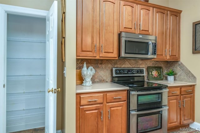 kitchen with light countertops, decorative backsplash, and stainless steel appliances