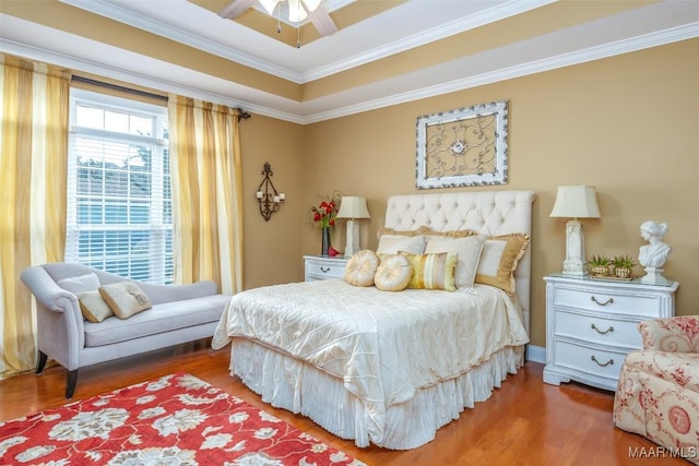bedroom with a raised ceiling, ornamental molding, and wood finished floors