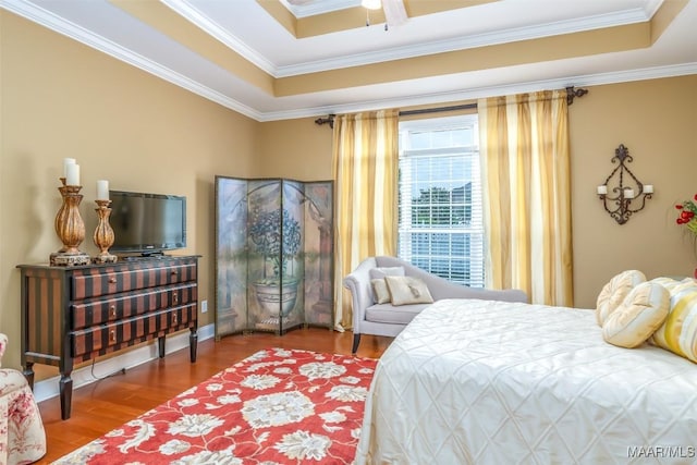 bedroom with ornamental molding, wood finished floors, and a raised ceiling
