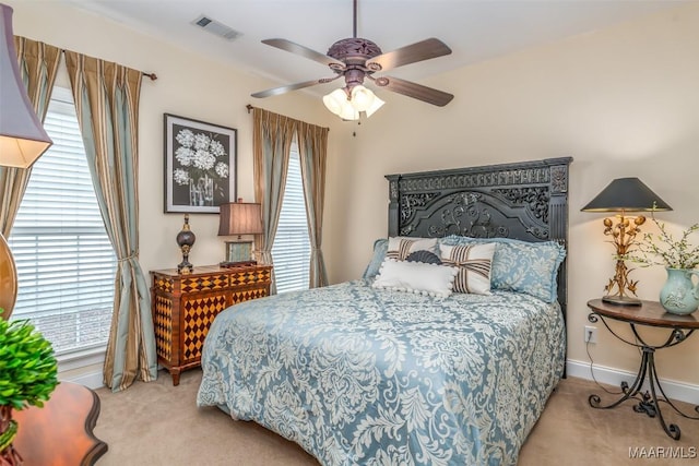 carpeted bedroom with a ceiling fan, baseboards, visible vents, and multiple windows