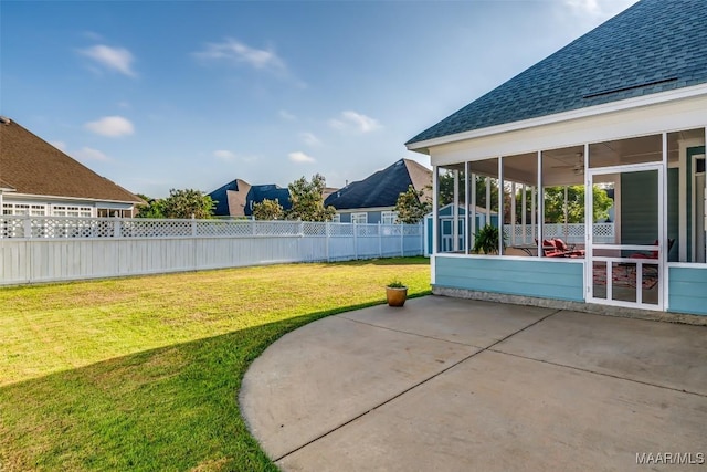 view of yard featuring an outbuilding, a sunroom, a patio area, fence, and a storage unit