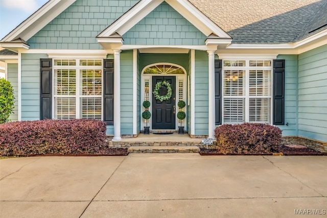view of exterior entry with a shingled roof