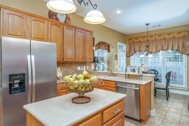 kitchen featuring backsplash, visible vents, appliances with stainless steel finishes, a sink, and a peninsula