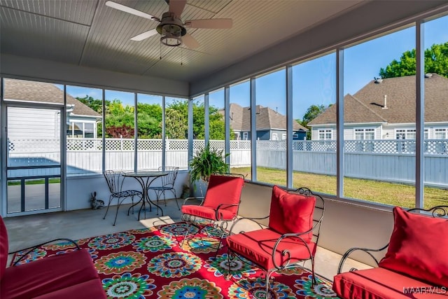 sunroom with a healthy amount of sunlight, a residential view, and a ceiling fan