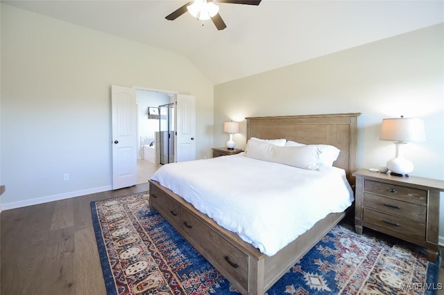 bedroom featuring wood finished floors, baseboards, a ceiling fan, ensuite bath, and vaulted ceiling