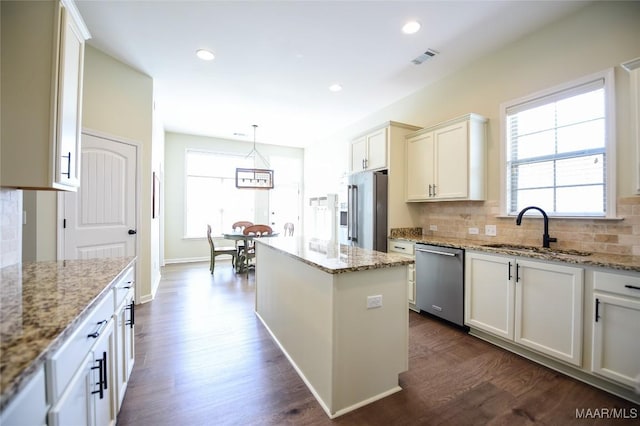 kitchen featuring decorative backsplash, dark wood-style flooring, a sink, a wealth of natural light, and stainless steel appliances