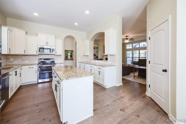 kitchen with white cabinets, stainless steel appliances, a ceiling fan, and decorative backsplash