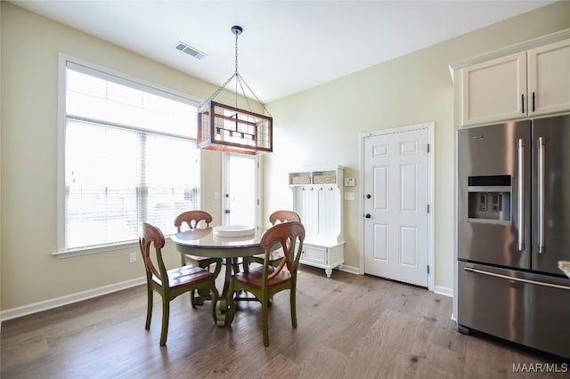 dining space with baseboards, visible vents, and wood finished floors
