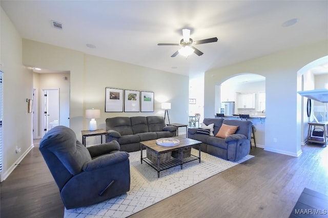 living area with ceiling fan, arched walkways, baseboards, wood finished floors, and visible vents