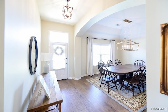 dining area featuring visible vents, dark wood-style flooring, baseboards, a chandelier, and arched walkways