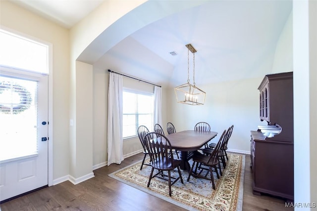 dining room featuring arched walkways, a chandelier, dark wood finished floors, baseboards, and visible vents