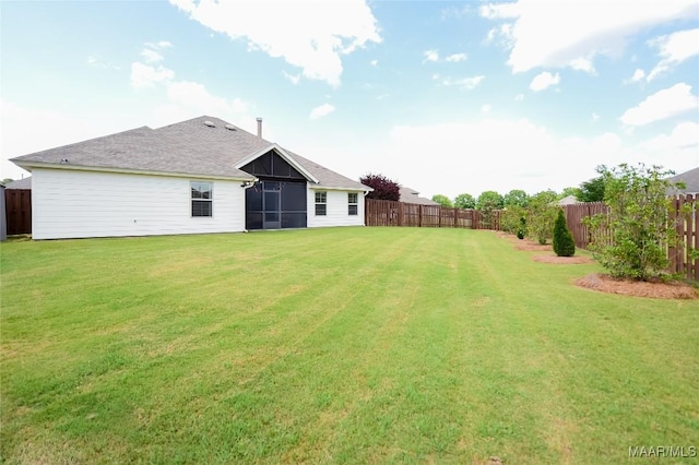 rear view of house with a lawn, a fenced backyard, and a sunroom