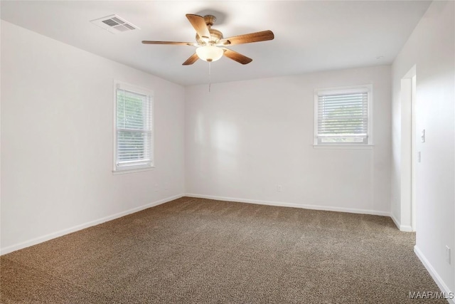 carpeted empty room with baseboards, ceiling fan, and visible vents