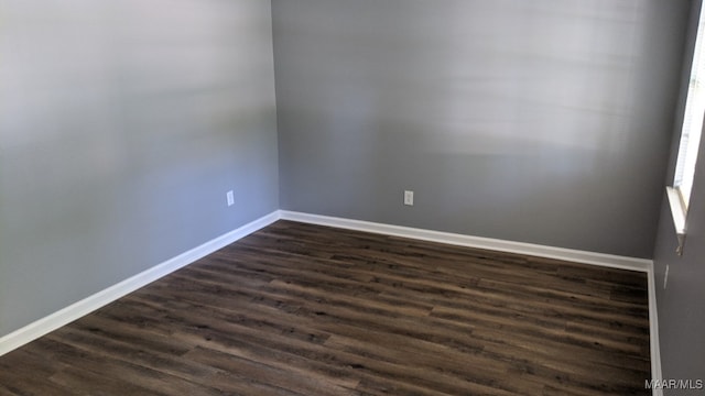 unfurnished room featuring baseboards and dark wood-style floors