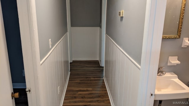 corridor featuring a sink, dark wood finished floors, and a decorative wall
