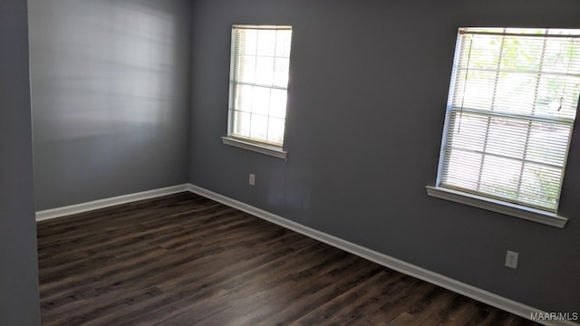 spare room featuring baseboards and dark wood-type flooring