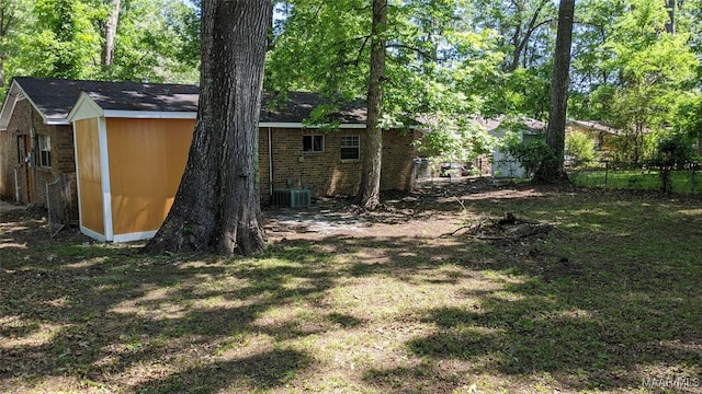 view of yard featuring a storage unit, an outdoor structure, fence, and central AC unit