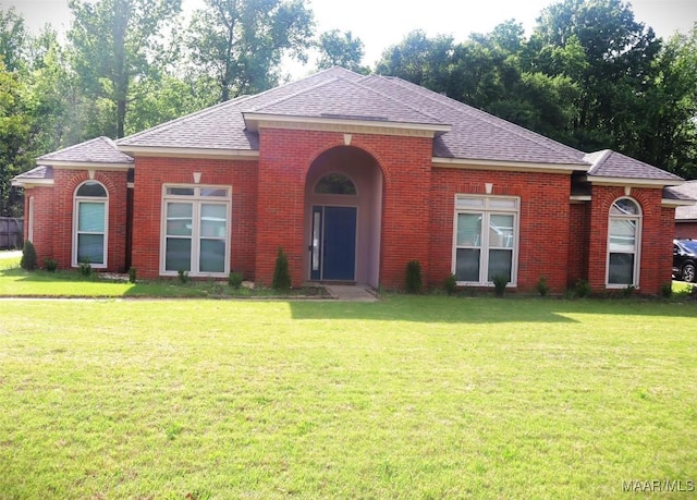 single story home featuring brick siding, a front lawn, and roof with shingles