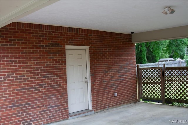 entrance to property featuring fence, a patio, and brick siding