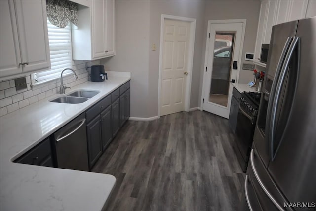 kitchen featuring dark wood-style flooring, appliances with stainless steel finishes, tasteful backsplash, a sink, and white cabinets