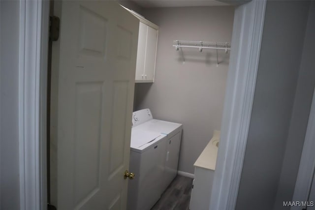 laundry room with cabinet space, baseboards, washing machine and dryer, and wood finished floors