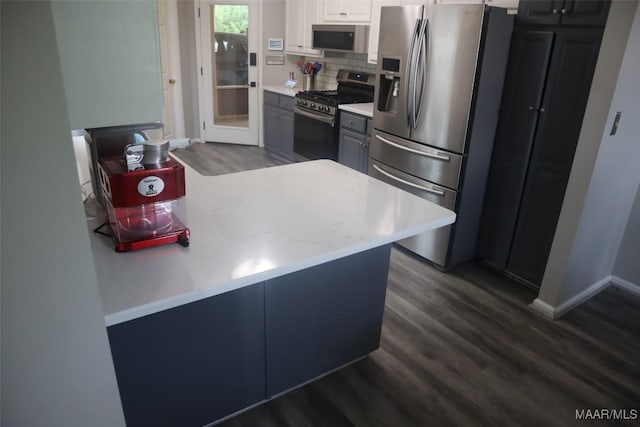 kitchen featuring light countertops, baseboards, appliances with stainless steel finishes, and dark wood-style floors