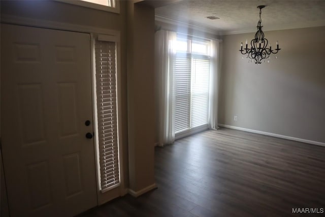 foyer with crown molding, visible vents, baseboards, dark wood-style floors, and a notable chandelier