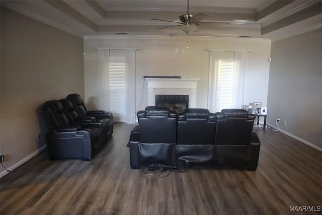 living area featuring ornamental molding, wood finished floors, baseboards, a raised ceiling, and a ceiling fan