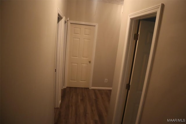 corridor featuring baseboards and dark wood-style floors