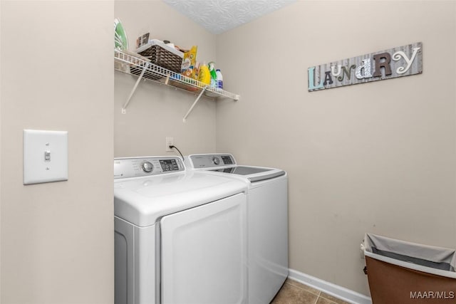 clothes washing area featuring independent washer and dryer, light tile patterned floors, laundry area, and baseboards